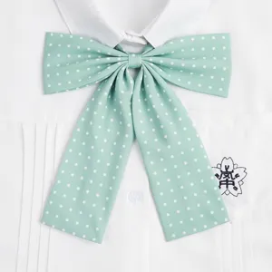 Primo piano di un papillon verde menta a pois abbinato a una camicia da uniforme scolastica.