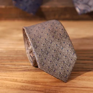 Detail shot of a vintage brown men's tie featuring a stylish blue dot pattern and texture.