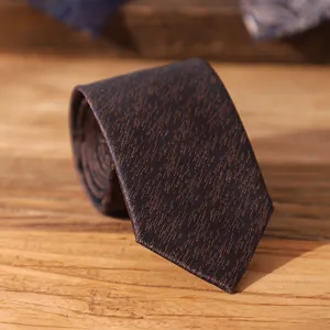 Detailed close-up view of dark brown textured mens necktie on rustic wooden surface.