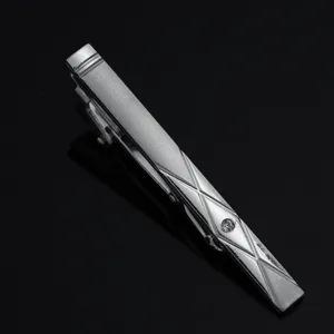 Close-up detail shot of a silver men's tie clip featuring geometric lines and crystal.