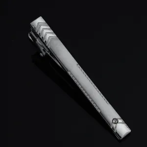 Detailed close-up of a sleek silver men's tie clip featuring geometric chevron patterns.