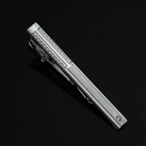 Close-up detail of silver metal tie clip with geometric pattern and crystal for men.