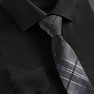 Close-up detail shot of a classic men business plaid tie paired with a dark formal dress shirt.