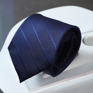 Detailed view of dark blue striped formal necktie fabric texture and fine craftsmanship.