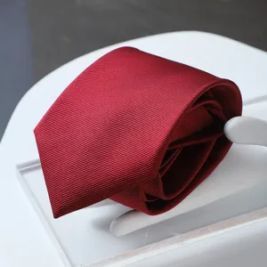 Close-up shot of fine twill texture on burgundy men's formal business necktie detail.