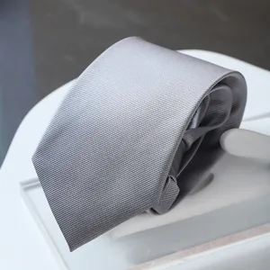 Close-up of a sleek grey striped business necktie neatly folded on a white display stand.