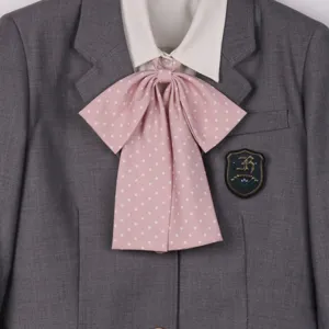 Detailed view of grey jk uniform blazer with white shirt and pink polka dot bow tie.
