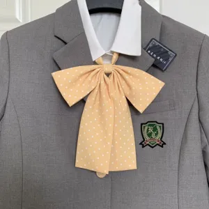 Detailed view of cute JK uniform yellow polka dot bow tie with grey blazer and white shirt.