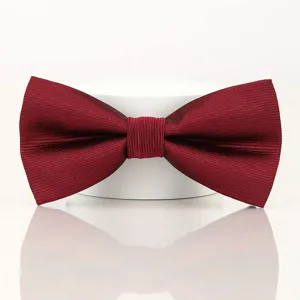 Burgundy men's bow tie fabric detail showing fine ribbed texture and neat knot craftsmanship.