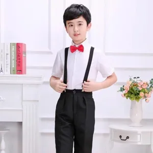 Vue détaillée de nœud papillon rouge pour enfant, porté avec chemise blanche et bretelles noires.