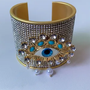 Primo piano dettagliato del bracciale rigido dorato malocchio con strass scintillanti.