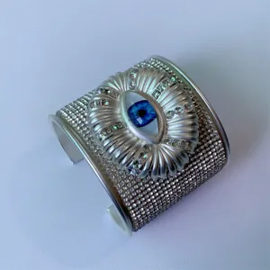 Bracciale cuff largo malocchio in metallo con strass scintillanti, accessorio moda aperto.