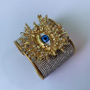 Vista di dettaglio dello splendido bracciale rigido dorato largo con occhio malvagio e strass.