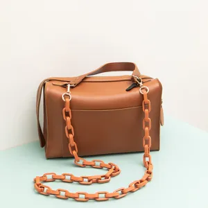 Detailaufnahme der modischen braunen Kastenhandtasche mit klobigem Kettenriemen im Stil.