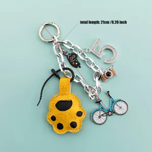 Cute cat paw keychain detail showing metal charms like bicycle camera and number five pendant.