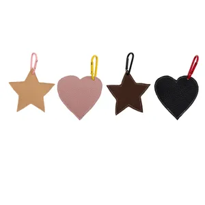 Close-up detail of leather star and heart bag charms with colorful metal carabiners.