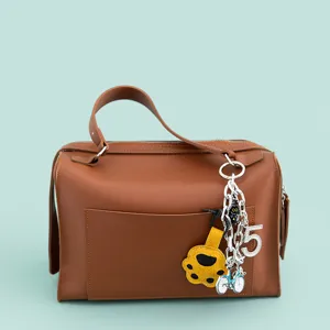 Stylish brown leather handbag featuring unique metal chains and cute multi-charms decoration.
