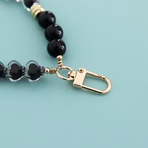 Phone charm strap connector with black beads, faceted heart beads and gold lobster clasp.