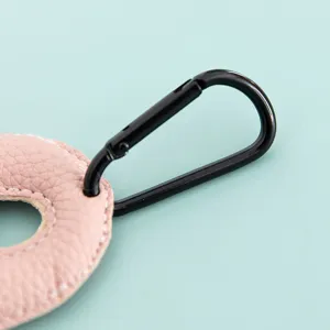 Primo piano del dettaglio del portachiavi con lettera in ecopelle rosa e moschettone nero.