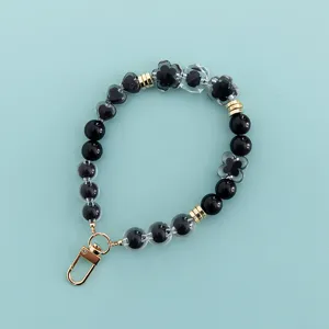 Detailed view of black and clear beaded phone wrist strap with cute heart and flower charms.
