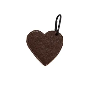 Brown heart leather keychain bag charm detail shot featuring delicate white stitching.