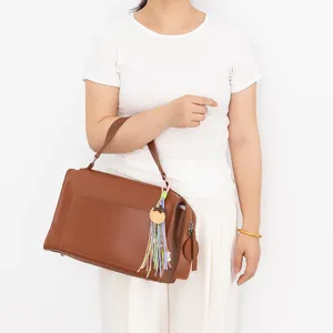 Vue détaillée du sac à main en cuir marron avec charm de sac tissé DIY coloré.