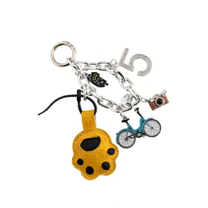 Close-up detail view of the cute cartoon cat paw, bicycle and camera keychain pendant charm.