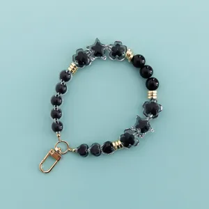 Detailed close-up view of the black beaded phone lanyard, showcasing crystal star and flower charm details.