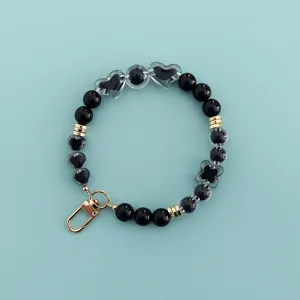 Black and transparent beaded phone charm with heart and clover charms, cute DIY accessory.