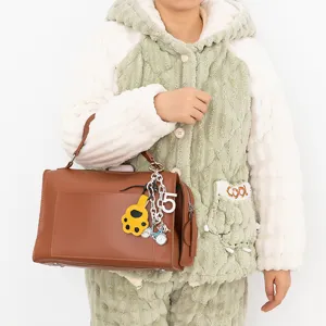 Brown handbag with cute cat paw and bicycle keychain charms, stylish women accessory.