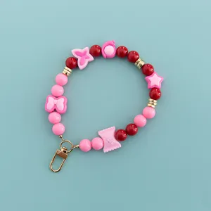 Detailed view of pink and red beaded wristlet strap, cute candy and star charms with gold clasp.