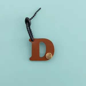 Gros plan détail d'un porte-clés lettre D minimaliste en cuir PU marron élégant.