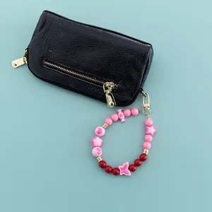 Black leather coin pouch showcased with cute pink and red candy bead strap charm detail.