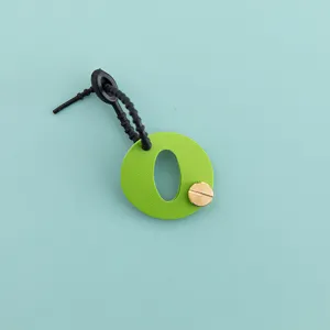 Vue détaillée du charm de sac lettre O en cuir PU vert avec une boucle noire et vis.