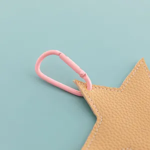 Close up detail shot of a star shaped leather keychain bag charm with pink metal carabiner.