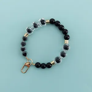 Chic black and clear bead phone charm with heart accents and gold lobster clasp for accessories.
