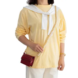 Vue détaillée du mini sac bandoulière rouge effet croco avec chaîne perles et or.