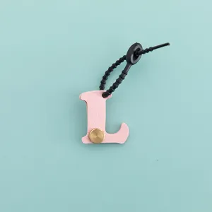 Porte-clés lettre L en cuir PU rose avec rivet métallique et lanière noire, vue détaillée.