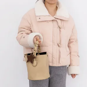 Detail shot of a beige leather bucket bag with a cute brown star charm and gathered handle.