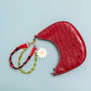 Red crescent handbag with beaded strap, colorful braided handle and cute daisy charm.