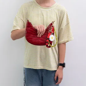 Red patent leather crescent shoulder handbag with colorful woven strap and daisy charm