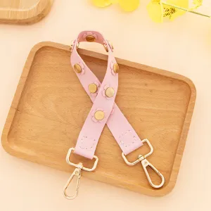 Courte bandouliere de sac en cuir PU rose avec rivets fleurs et fermoirs dores, detail.