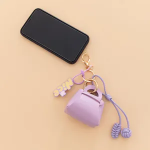 Detail view of a cute purple PU mini handbag keychain charm with a nice letter pendant.