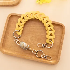 Sangle de sac tressee en cuir PU jaune avec fermoirs metalliques et perle style marbre.