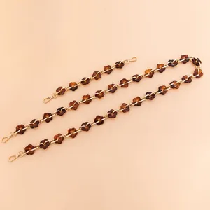 Acrylic flower bag chain and phone strap detail featuring brown resin flowers with gold links.