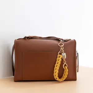Détail de sac à main en cuir PU marron avec une élégante lanière de chaîne tressée jaune.