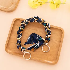 Primer plano de pañuelo de seda azul oscuro entrelazado con cadena dorada y lazo.