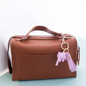 Vue détaillée d'un porte-clés éléphant en cuir violet avec anneau métallique sur sac marron.