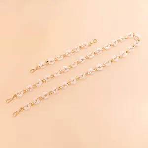 Detailed view of gold chain with white acrylic flowers for DIY bag straps or phone accessories.
