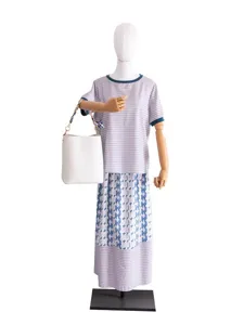 Bolso cubo blanco con cadena de metal y correa de bufanda, combinado con un vestido de rayas.